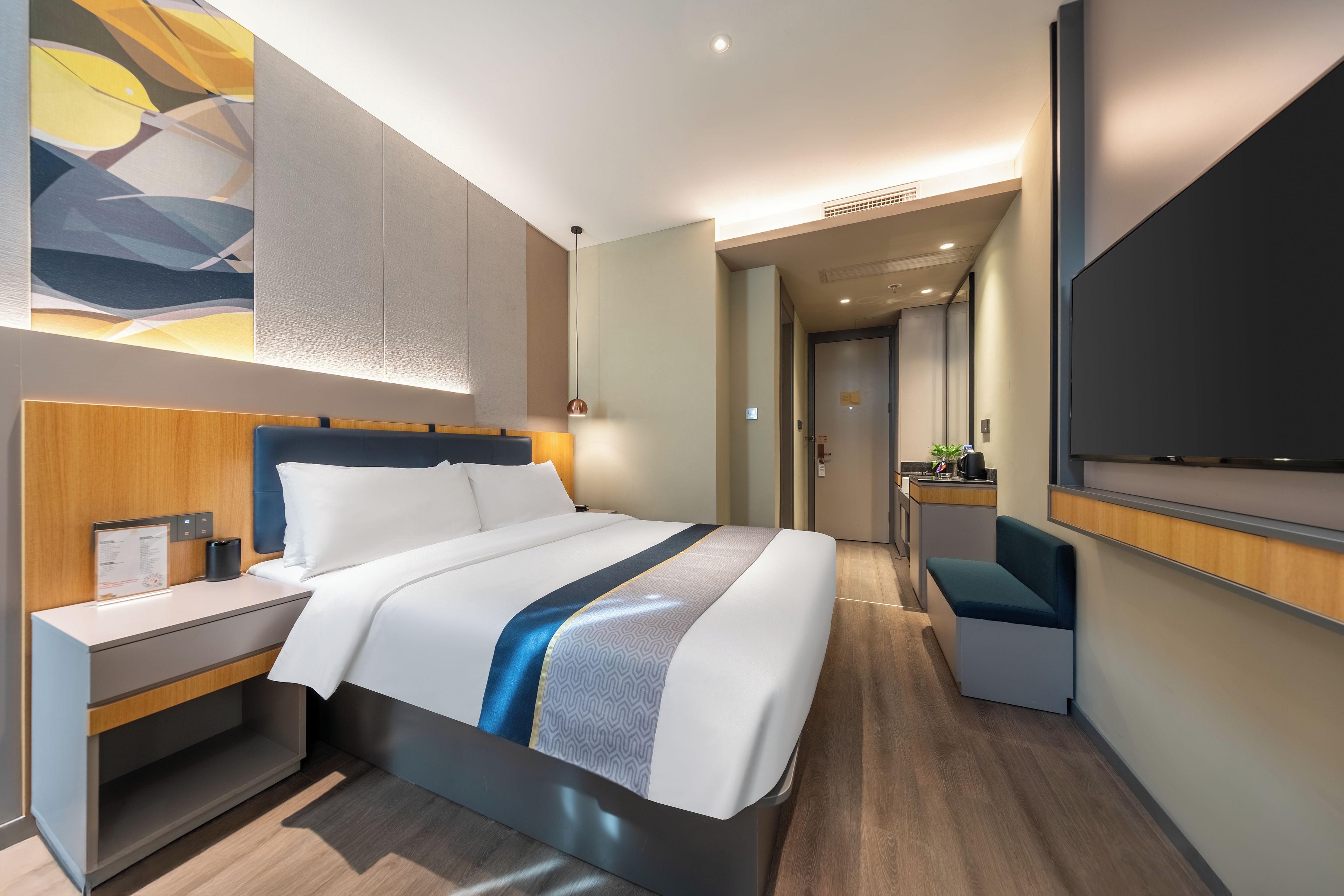 Habitación de hotel moderna con una cama grande, mesitas de noche, un escritorio y un televisor de pantalla plana.