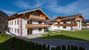 Eine zweistöckige Chalet mit Holzbalkonen, weißen Wänden und blauem Himmel.
