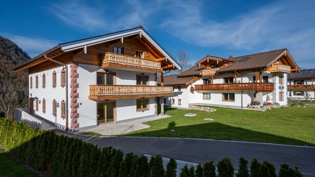 Un chalet à deux étages doté de balcons en bois, de murs blancs et surplombant un ciel dégagé.