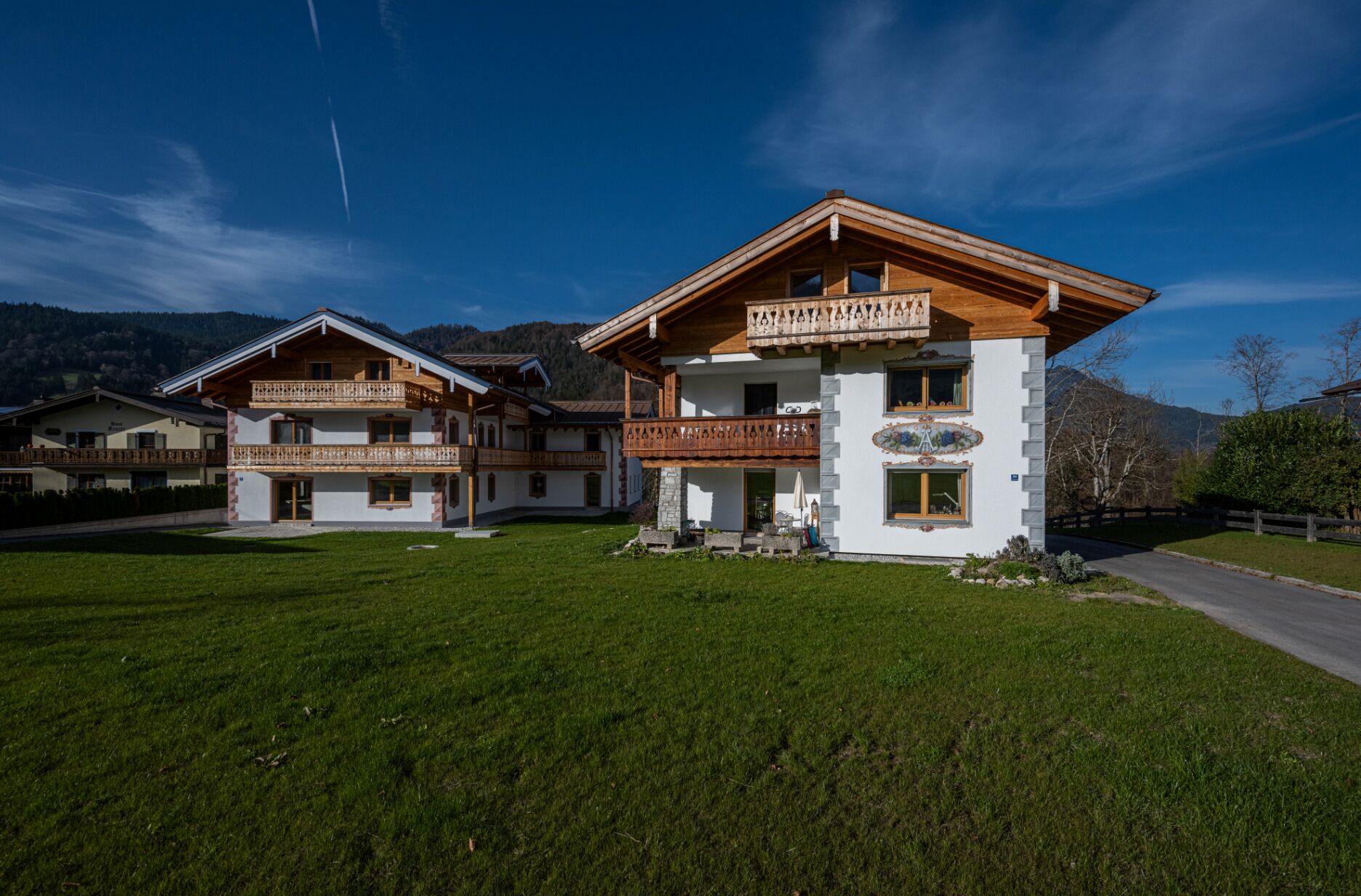 A two-story chalet with wooden balconies and a mountain backdrop.