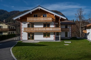 A two-story chalet with a wooden balcony, a stone pathway, and a mountain backdrop. - Schönfeldspitze Vacation Rental, 145 square meters with 4 bedrooms (Schönau am Königssee)
