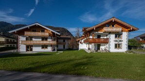 Eine zweistöckige Chalet mit Balkon, umgeben von einem gepflegten Rasen und Blick auf die Berge.