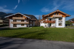 A two-story chalet with a balcony, surrounded by a well-maintained lawn and a mountain backdrop. - Schönfeldspitze Vacation Rental, 145 square meters with 4 bedrooms (Schönau am Königssee)