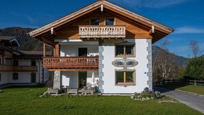Un bâtiment en bois à deux étages, doté d’un balcon, de fondations en pierre et d’un emblème décoratif sur la façade.