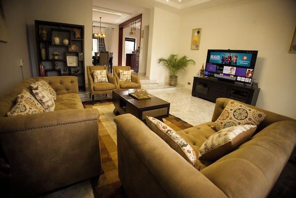 A living room with a sofa set, a coffee table, a television, and a bookshelf.