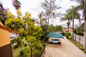 Una strada privata che conduce a una residenza, con un'auto parcheggiata, immersa nel verde e alberi.