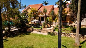 A residential building with a red-tiled roof, a stone pathway leading to the entrance, and a well-maintained lawn.