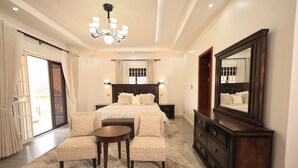 A bedroom with a large bed, a sitting area, a dresser, a mirror, and a chandelier. - Vista Palms Retreat 3 bed and 2 bath Private Hilltop house in Bunamwaya Kampala. (Kampala)