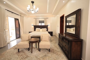 A bedroom with a large bed, a sitting area, a dresser, a mirror, and a chandelier. - Vista Palms Retreat 3 bed and 2 bath Private Hilltop house in Bunamwaya Kampala. (Kampala)