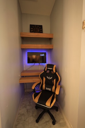 A gaming setup with a monitor, chair, and shelves.