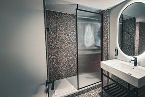 A modern bathroom with a shower enclosure, a sink, and a large mirror. - The Village Hotel Sheffield (Sheffield)
