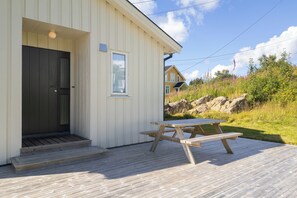 A wooden deck with a picnic table, a door, and a window.