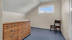 A room with a wooden dresser, a chair, and a window with a view.