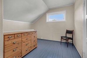 A room with a wooden dresser, a chair, and a window with a view.
