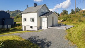 A two-story house with a gravel driveway and a small patio area.