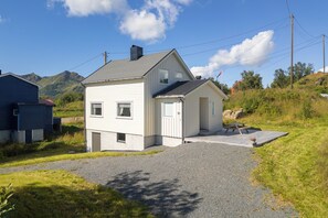 A two-story house with a gravel driveway and a small patio area.