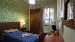 A bedroom with a bed, a wardrobe, a desk with a television, and a window with curtains. - Sant Agostino Rooms (Milan)