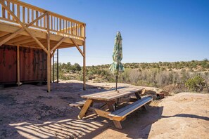 Eine Holzterrasse mit Picknicktisch und Sonnenschirm, umgeben von einer Wüstenlandschaft.