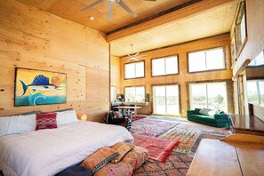A spacious room with a large bed, a desk, and a green sofa.