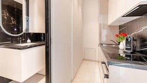 A modern kitchen with a black marble countertop, a built-in oven, and a coffee machine. - Luxury Apartment in Nice Plage (Nice)