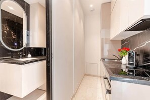 A modern kitchen with a black marble countertop, a built-in oven, and a coffee machine. - Luxury Apartment in Nice Plage (Nice)