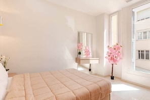 Ein Schlafzimmer mit einem Bett, einem Schminktisch mit Spiegel und einem Fenster.
