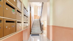 A hallway with a staircase leading to a room. There are metal filing cabinets on the left. - Luxury Apartment in Nice Plage (Nice)