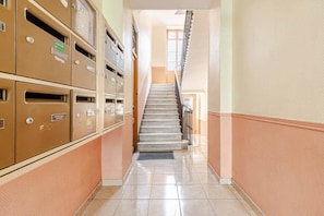 A hallway with a staircase leading to a room. There are metal filing cabinets on the left. - Luxury Apartment in Nice Plage (Nice)
