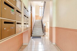 Ein Korridor mit einer Treppe, die zu einer oberen Etage führt, mit einer Reihe von Metallbriefkästen links.