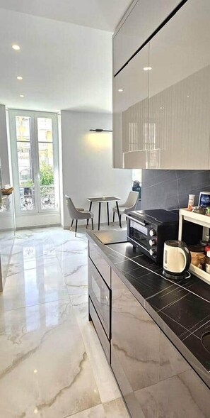 Eine moderne Küche mit schwarzem Arbeitsplatz, einem integrierten Backofen und einem Essbereich mit Tisch und Stühlen.