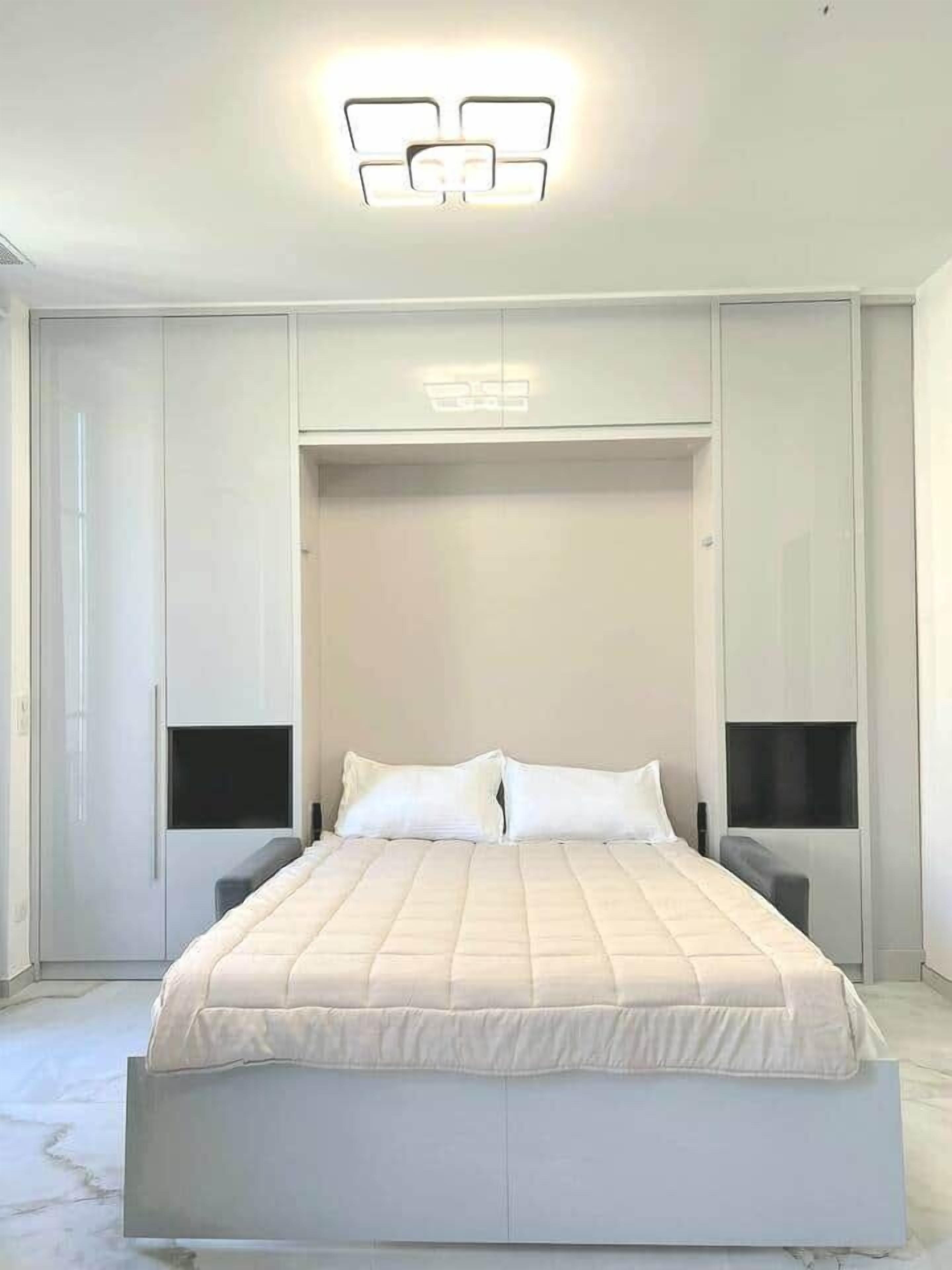 Ein modernes Schlafzimmer mit einem großen Bett, Einbauschränken und einer Deckenleuchte.