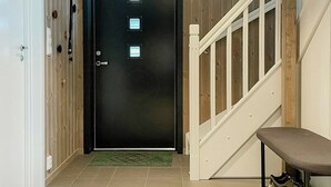 A hallway with a black door, a white bench, and a staircase. - Modern cabin with panoramic views in Vrådal (Vrådal)