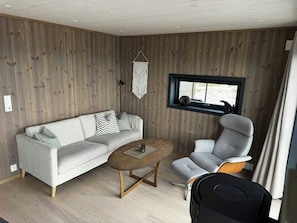 A modern living room with a sectional sofa, a round coffee table, and a grey armchair. - Modern cabin with panoramic views in Vrådal (Vrådal)