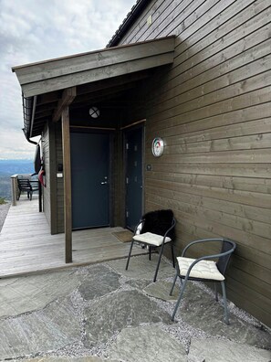 A wooden building with a covered porch, outdoor seating, and a view of the mountains. - Modern cabin with panoramic views in Vrådal (Vrådal)