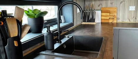 A modern kitchen with a sink, countertop, and wooden cutting board.