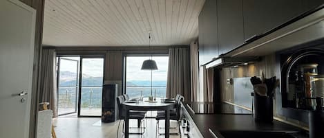 Una cocina moderna con una isla central, un comedor con vistas y un techo de madera.