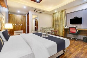 A hotel room with a bed, a desk, a chair, a television, and an air conditioning unit. - Royal Saffron by Stay Pattern- City Center (Srinagar)