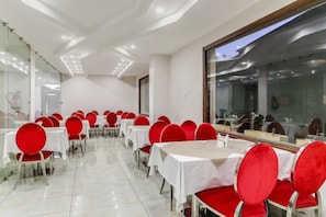 A conference room with rows of tables and chairs, large windows, and a modern ceiling design. - Royal Saffron by Stay Pattern- City Center (Srinagar)
