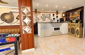 A hotel lobby with a foosball table, a reception desk, and a wall with geometric art. - Royal Saffron by Stay Pattern- City Center (Srinagar)