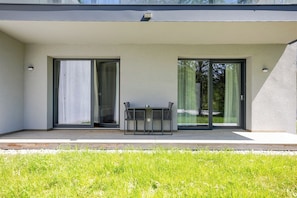Un edificio moderno con techo plano, grandes puertas correderas de vidrio y un patio con mesa y sillas.