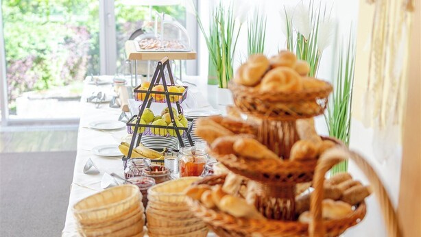 Una mesa de buffet con diferentes alimentos y una presentación de pan de tres niveles.