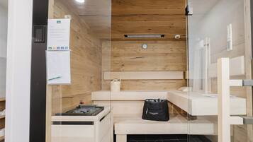 A sauna room with wooden walls, a bench, a bucket, and a bag.