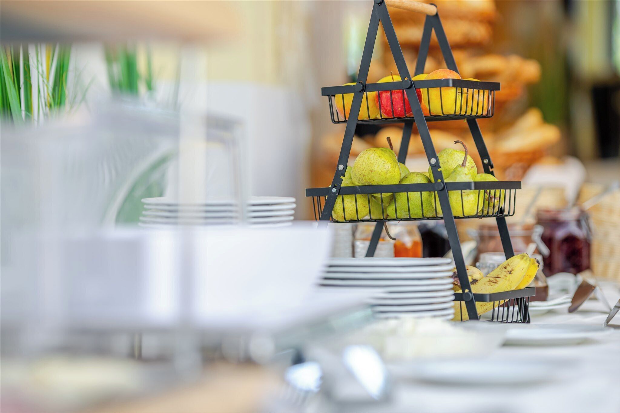 A buffet setup with a fruit display and stacked plates.