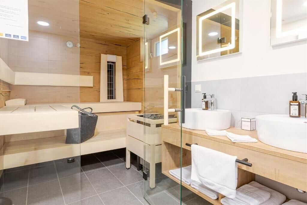 A modern bathroom with a wooden vanity, a glass shower enclosure, and a large mirror.