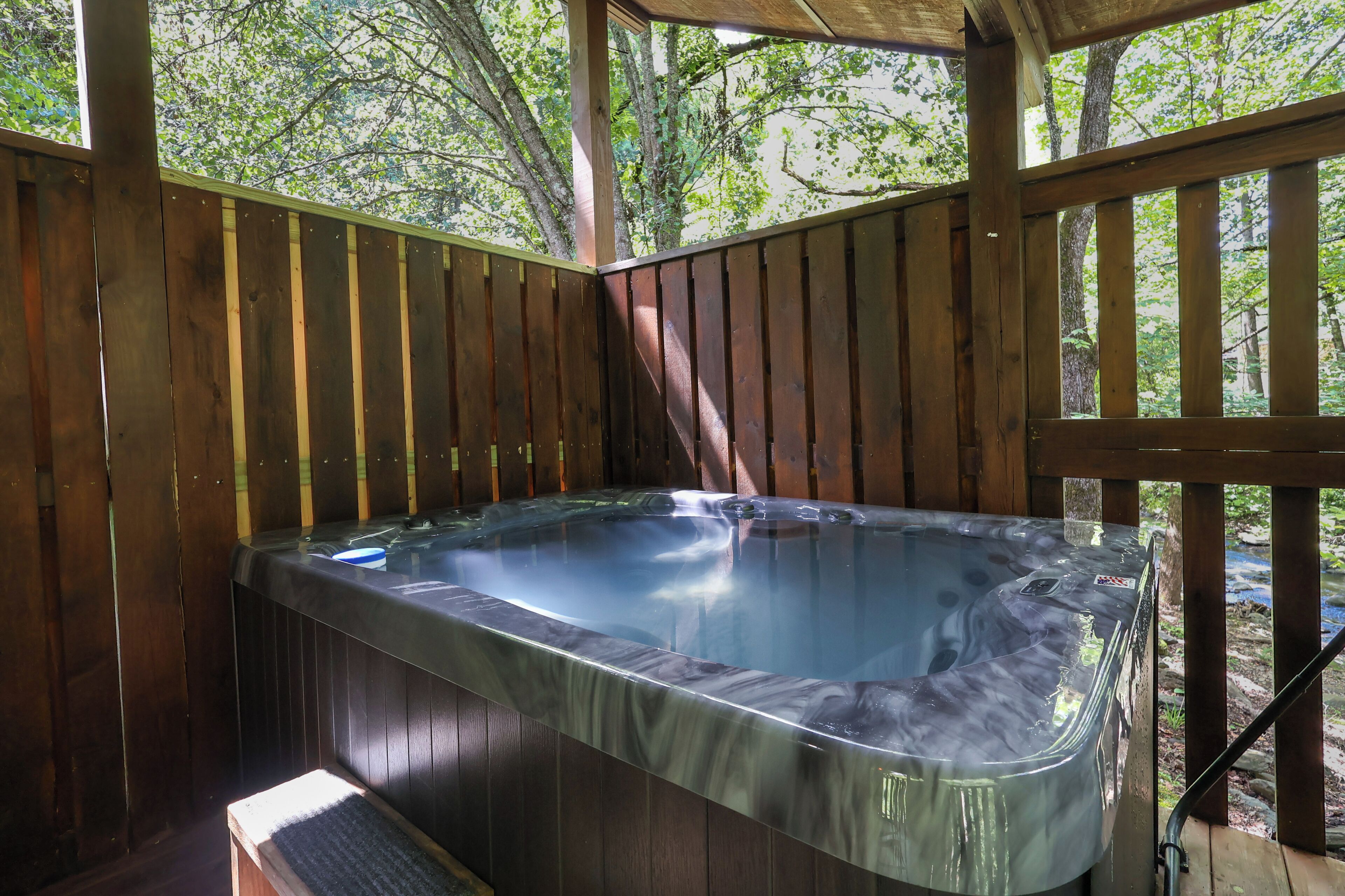 Un jacuzzi en una estructura de madera con vistas a árboles.