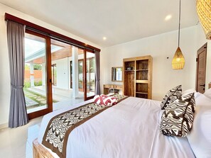 Una camera da letto con un letto grande, un armadio in legno, una scrivania e vista sull'esterno.