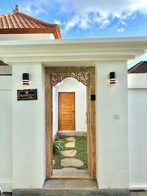 A villa entrance with a wooden door, a decorative archway, and a sign reading 'MARIGOLD Villa.'