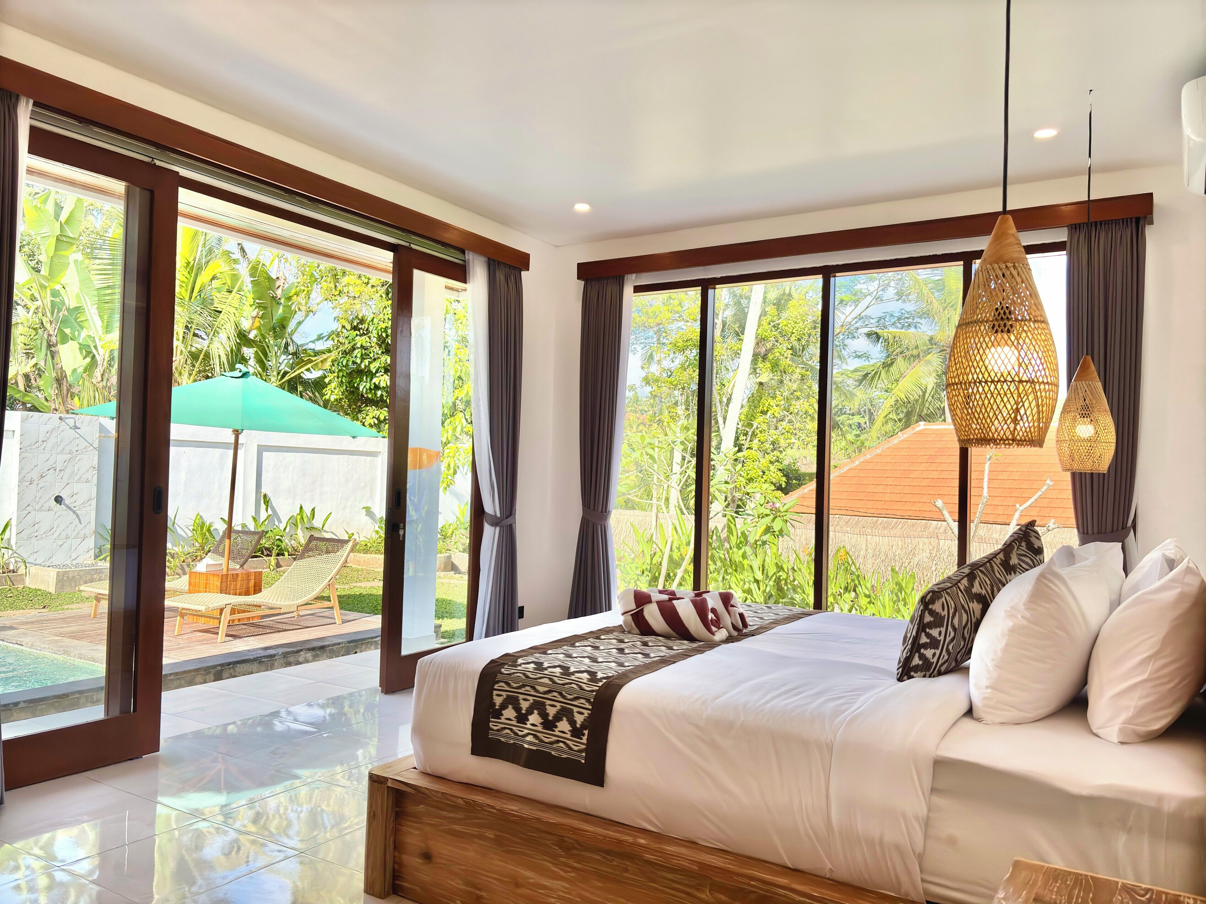 Ein geräumiges Schlafzimmer mit einem großen Bett, Blick auf einen Garten und einer Glasschiebetür, die nach draußen führt.