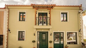 Un edificio de dos pisos con una puerta verde, varias ventanas y plantas en macetas.