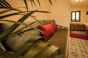 A room with a sofa, a red pillow, a patterned rug, and a window with a view.